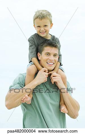 Picture - Man carrying son on his shoulders, both smiling at camera, portrait. Fotosearch