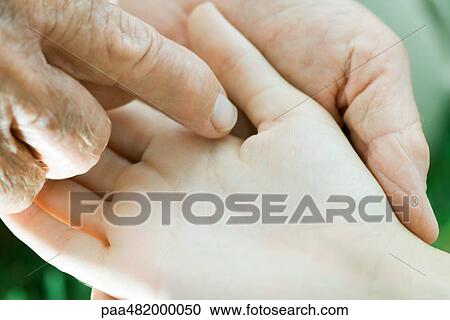 Stock Image - Man touching child's palm, extreme close-up. Fotosearch