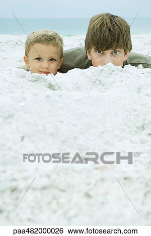 Two brothers at the beach, peeking over sand at camera View Large Photo Image Stock Photograph - Two brothers at the beach, peeking over sand at camera. Fotosearch