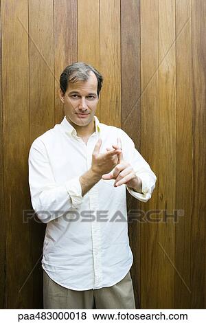 Man standing in front of wood paneling, making gesture with hands, looking at camera View Large Photo Image Stock Photo - Man standing in front of wood paneling, making gesture with hands, looking at camera. Fotosearch