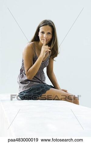 Teenage girl sitting, finger on lips, looking at camera View Large Photo Image Stock Photo - Teenage girl sitting, finger on lips, looking at camera. Fotosearch