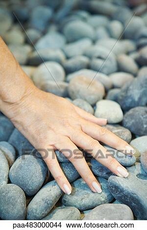 Picture - Woman touching pebbles, cropped view of hand. Fotosearch