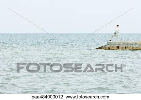 Man standing at the end of pier, talking on cell phone, in the distance View Large Photo Image Stock Image - Man standing at the end of pier, talking on cell phone, in the distance. Fotosearch
