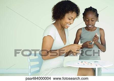 Mother and daughter playing pick up sticks together at table, both smiling View Large Photo Image Picture - Mother and daughter playing pick up sticks together at table, both smiling. Fotosearch