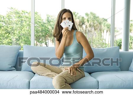 Teenage girl holding cards in front of face, looking at camera View Large Photo Image Picture - Teenage girl holding cards in front of face, looking at camera. Fotosearch
