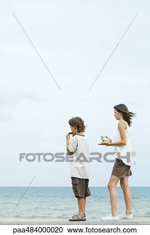 Teenage girl playing tambourine at the beach, brother playing harmonica beside her, both looking at view View Large Photo Image Stock Image - Teenage girl playing tambourine at the beach, brother playing harmonica beside her, both looking at view. Fotosearch