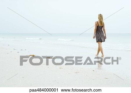 Woman in sundress walking along beach, rear view View Large Photo Image Stock Image - Woman in sundress walking along beach, rear view. Fotosearch