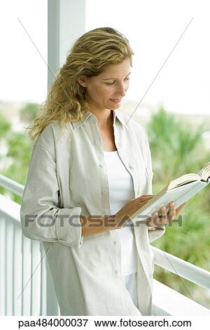 Woman standing on porch reading book View Large Photo Image Stock Photo - Woman standing on porch reading book. Fotosearch