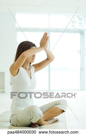 Young woman sitting in lotus position, arms raised, clasped hands View Large Photo Image Stock Image - Young woman sitting in lotus position, arms raised, clasped hands. Fotosearch