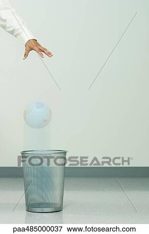 Businessman dropping globe into trash can, cropped view View Large Photo Image Stock Photo - Businessman dropping globe into trash can, cropped view. Fotosearch