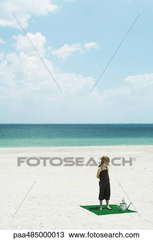 Girl standing on square of artificial turf on beach, next to watering can, high angle view View Large Photo Image Stock Image - Girl standing on square of artificial turf on beach, next to watering can, high angle view. Fotosearch