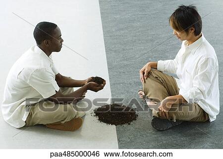 Two males sitting face to face, one holding out handful of soil View Large Photo Image Stock Photograph - Two males sitting face to face, one holding out handful of soil. Fotosearch
