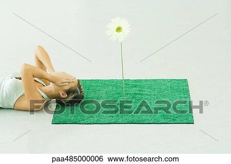 Woman lying with head on square of artificial turf, covering face View Large Photo Image Stock Photograph - Woman lying with head on square of artificial turf, covering face. Fotosearch