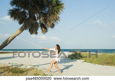 Woman pulling palm tree with rope View Large Photo Image Stock Image - Woman pulling palm tree with rope. Fotosearch
