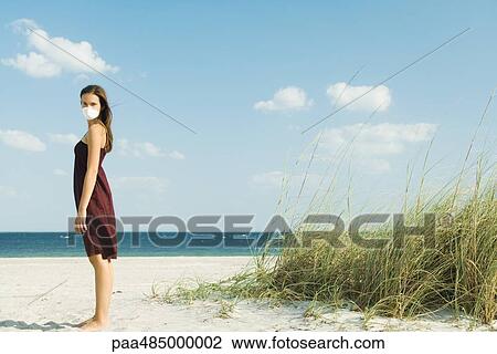 Woman standing on beach wearing pollution mask, turning face toward camera View Large Photo Image Stock Image - Woman standing on beach wearing pollution mask, turning face toward camera. Fotosearch
