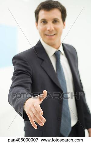 Businessman holding hand out toward camera, smiling, personal perspective View Large Photo Image Stock Photo - Businessman holding hand out toward camera, smiling, personal perspective. Fotosearch