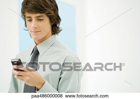 Businessman looking down at cell phone, close-up View Large Photo Image Stock Photo - Businessman looking down at cell phone, close-up. Fotosearch