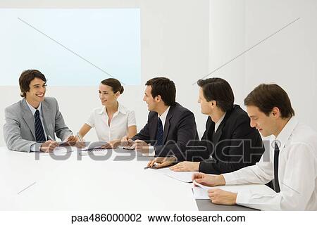 Group of business associates sitting together at conference table, smiling View Large Photo Image Stock Image - Group of business associates sitting together at conference table, smiling. Fotosearch