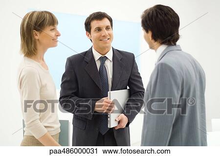 Three business associates standing, talking together, smiling View Large Photo Image Stock Image - Three business associates standing, talking together, smiling. Fotosearch
