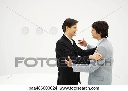 Two male business partners standing face to face, hands on each other's shoulders, smiling View Large Photo Image Picture - Two male business partners standing face to face, hands on each other's shoulders, smiling. Fotosearch