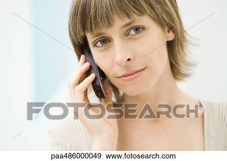 Stock Photo - Woman using cell phone, looking away, close-up. Fotosearch