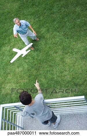 Boy standing on balcony, throwing toy airplane to grandfather standing below, high angle view View Large Photo Image Stock Image - Boy standing on balcony, throwing toy airplane to grandfather standing below, high angle view. Fotosearch