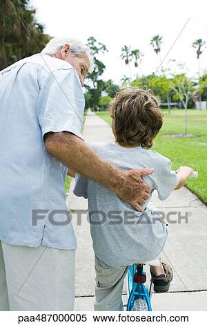 Grandfather teaching grandson to ride bicycle, rear view View Large Photo Image Stock Photography - Grandfather teaching grandson to ride bicycle, rear view. Fotosearch