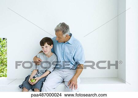 Man sitting with arm around grandson, chatting, both looking away View Large Photo Image Picture - Man sitting with arm around grandson, chatting, both looking away. Fotosearch