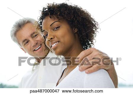 Man with arm around woman's shoulder, woman smiling at camera, side view View Large Photo Image Stock Photo - Man with arm around woman's shoulder, woman smiling at camera, side view. Fotosearch