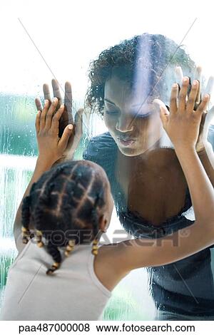 Mother and daughter making faces at each other through window, close-up View Large Photo Image Stock Photo - Mother and daughter making faces at each other through window, close-up. Fotosearch