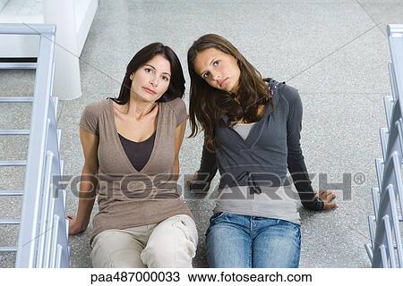 Mother and daughter sitting on the ground together, both looking up at camera View Large Photo Image Stock Image - Mother and daughter sitting on the ground together, both looking up at camera. Fotosearch