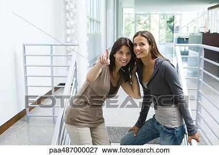 Woman standing on stairs with daughter, pointing, both looking up and smiling View Large Photo Image Stock Photo - Woman standing on stairs with daughter, pointing, both looking up and smiling. Fotosearch
