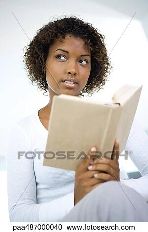 Young woman holding book, looking away, close-up View Large Photo Image Stock Image - Young woman holding book, looking away, close-up. Fotosearch