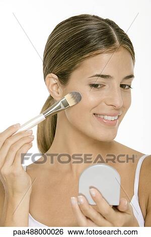 Woman applying blush, looking in hand mirror View Large Photo Image Stock Photograph - Woman applying blush, looking in hand mirror. Fotosearch