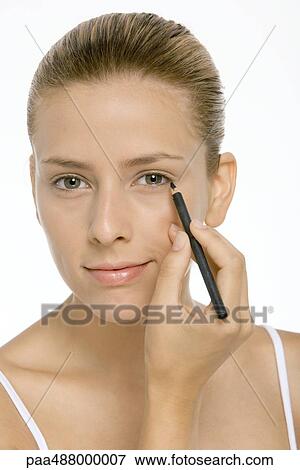 Woman applying eyeliner, smiling at camera, closeñup View Large Photo Image Stock Photo - Woman applying eyeliner, smiling at camera, closeñup. Fotosearch
