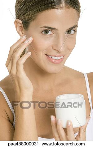 Woman applying moisturizer to face, smiling at camera View Large Photo Image Stock Image - Woman applying moisturizer to face, smiling at camera. Fotosearch