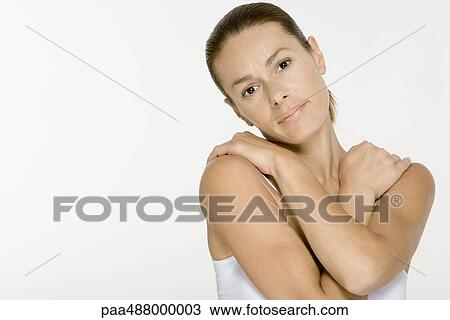 Stock Image - Woman folding arms across chest, looking at camera. Fotosearch
