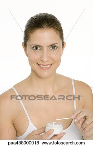 Woman holding cotton swab and jar of moisturizer, smiling at camera View Large Photo Image Stock Photo - Woman holding cotton swab and jar of moisturizer, smiling at camera. Fotosearch