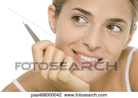 Woman holding tweezers, smiling and looking away View Large Photo Image Stock Image - Woman holding tweezers, smiling and looking away. Fotosearch