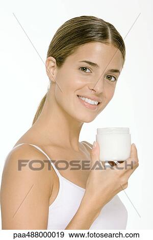 Woman holding up jar of skin cream, smiling at camera View Large Photo Image Stock Photo - Woman holding up jar of skin cream, smiling at camera. Fotosearch