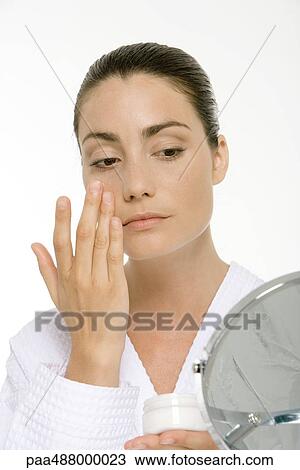 Woman looking into mirror, applying face cream View Large Photo Image Stock Image - Woman looking into mirror, applying face cream. Fotosearch