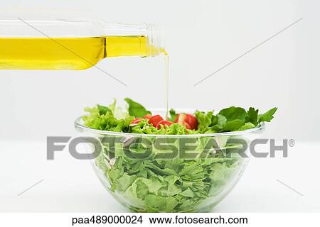 Picture - Olive oil being poured onto salad, close-up. Fotosearch