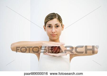 Woman balancing apple between hands, smiling at camera View Large Photo Image Stock Photograph - Woman balancing apple between hands, smiling at camera. Fotosearch