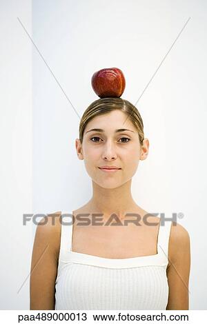 Woman balancing apple on her head, smiling at camera, portrait View Large Photo Image Stock Image - Woman balancing apple on her head, smiling at camera, portrait. Fotosearch