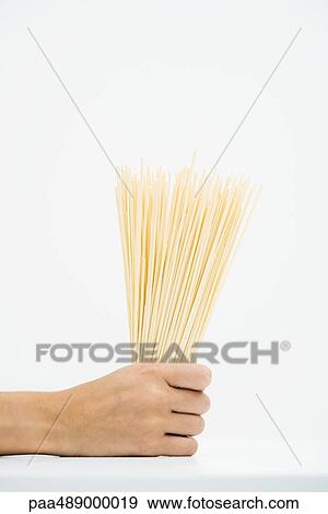 Stock Photo - Woman holding handful of dried pasta, cropped view of hand. Fotosearch