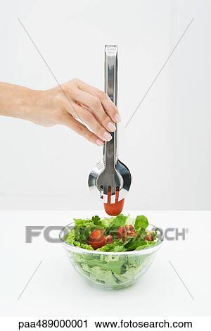 Woman picking tomato out of salad bowl using tongs, cropped view of hand View Large Photo Image Stock Image - Woman picking tomato out of salad bowl using tongs, cropped view of hand. Fotosearch