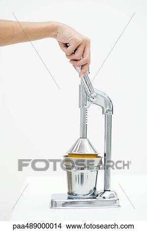 Picture - Woman pressing orange with citrus press, cropped view of hand. Fotosearch