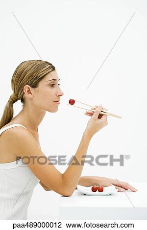 Young woman sitting, eating grape with chopsticks, side view View Large Photo Image Stock Image - Young woman sitting, eating grape with chopsticks, side view. Fotosearch