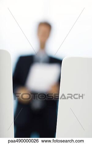 Blurred silhouette of businessman holding document, focus on foreground View Large Photo Image Stock Photograph - Blurred silhouette of businessman holding document, focus on foreground. Fotosearch