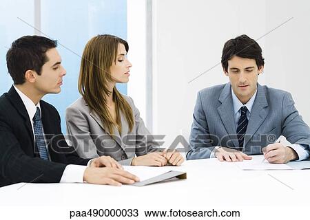 Business associates in meeting, man signing document while others watch View Large Photo Image Stock Image - Business associates in meeting, man signing document while others watch. Fotosearch